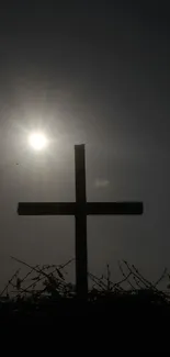 Silhouette of a cross against a sunrise sky.