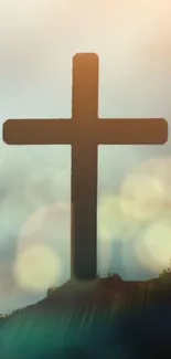 Silhouette of a cross against a vibrant sunset with bokeh effects.