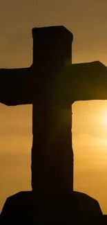 Silhouette of a cross against a golden sunset sky.