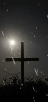 Silhouette of a cross with sunlight and raindrops in the background.