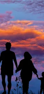 Family silhouette against a vibrant sunset sky with orange clouds.