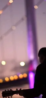 Silhouette of a guitarist with a glowing bridge at dusk.