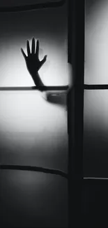 Silhouette of a hand on frosted glass panel in black and white tones.