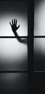 Silhouette of a hand on frosted glass background, creating a shadow effect.