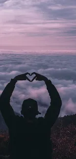 Silhouette forming heart against sunset sky over clouds.