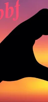 Silhouette heart made by hands at sunset with vibrant gradient.