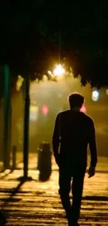 Silhouette of a man walking under a streetlight at night.