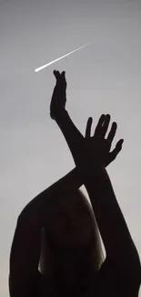 Silhouette of person with meteor in a gray sky.