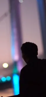 Silhouette of person against urban night backdrop with blurred lights.