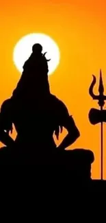 Silhouette of Lord Shiva with a trident against an orange sunset.