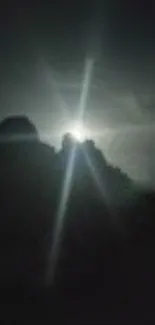 Moonlight silhouette of mountains against night sky.