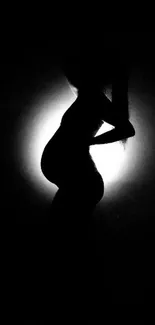 Silhouette of a pregnant woman against light background.