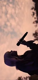 Silhouette of a singer holding a microphone against a dusky sunset sky.