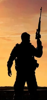 Silhouette of a soldier at sunset with vibrant orange sky.