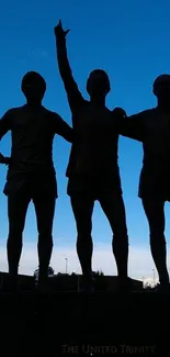 Silhouette of three statues against a vibrant blue sky.