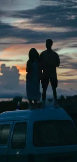 Silhouettes of people on a van roof at sunset with a dramatic sky background.