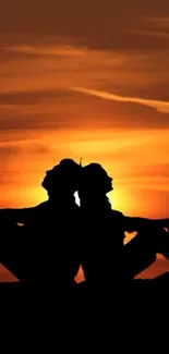 Silhouette of a couple against an orange sunset sky.