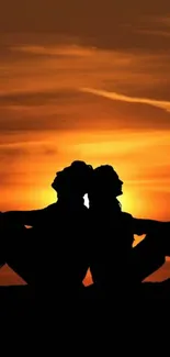 Silhouette of two figures against a vibrant sunset on a mobile wallpaper.