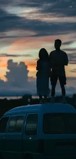 Silhouette of a couple standing on a van during sunset with a dramatic sky.