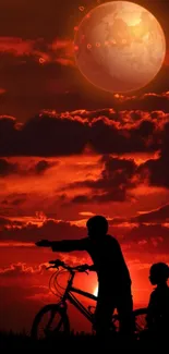 Silhouette of children with bicycle against a red sunset and glowing moon.