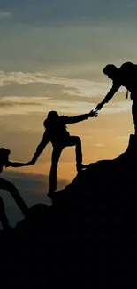 Silhouette of teamwork on a mountain during sunset.