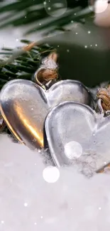 Silver heart ornaments with snow and greenery.