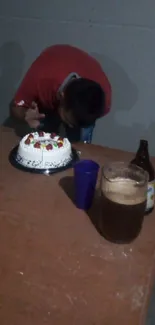 Simple celebration setting with a cake and drinks on a table in a dim room.