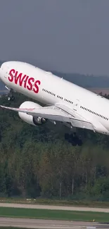 Swiss airplane taking off above a lush green forest.