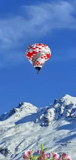 Colorful hot air balloon over snowy mountains and blue sky.