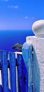 Serene blue ocean view with rustic white gate and clear sky.