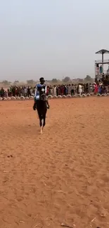 Lone rider on horse in desert with crowd in background.