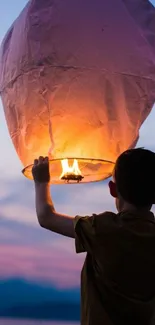 Boy releasing lantern at twilight.