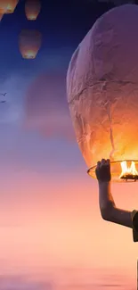 Sky lanterns glowing at sunset with birds in the sky.