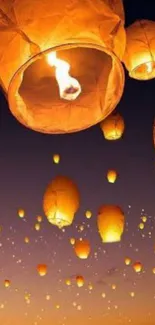 Sky lanterns illuminate the night sky with a warm orange glow.