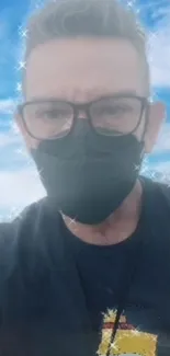 Person with mask and glasses against a cloudy sky backdrop.