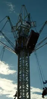 Silhouette of a carnival ride against a blue sky with floating swings.