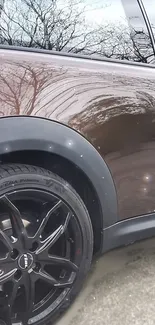 Close-up of a sleek black car with shiny wheels and glossy finish.