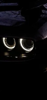 Close-up of black car headlights in dark setting.