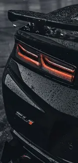 Sleek black car with glowing tail lights in the rain.