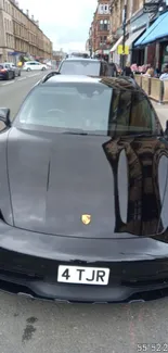 Sleek black car parked on a vibrant city street, showcasing urban automotive design.