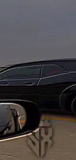 Sleek black car driving down an open highway with a dynamic background.