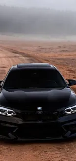 Sleek black car on a dirt road with a foggy background.