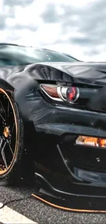 Sleek black car with golden rims on a cloudy day.