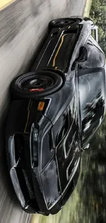 Sleek black car speeding on an empty road with blurred background.