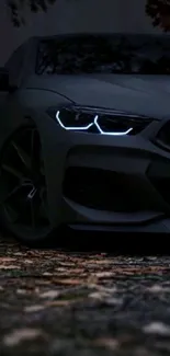 Sleek black car with glowing headlights on a dark background.