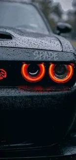 Sleek black car with illuminated red headlights in the rain.