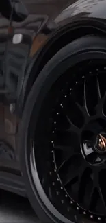 Close-up of a sleek black car wheel with a glossy finish.