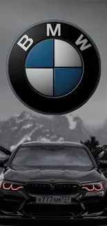 Sleek black car with prominent logo against a mountain background in grayscale.