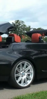 Black convertible car with red seats open in the sun.