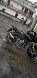 Sleek black motorcycle parked on cobblestone street.